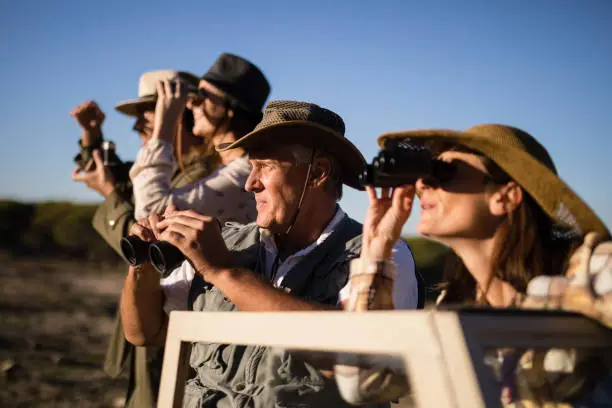Photo of Friends looking through binoculars during safari vacation