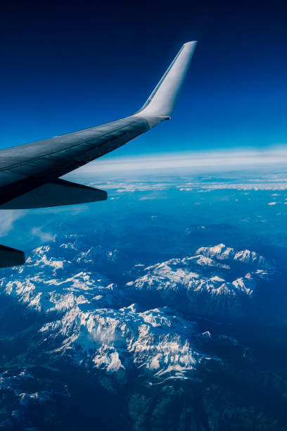 istock Wing of plane flying over clouds and mountains. 879928760