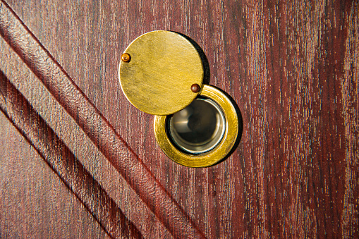 Peephole on wooden door - judas hole spyhole.