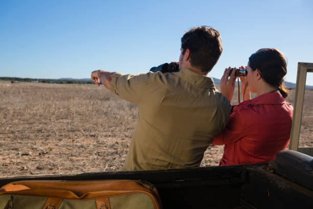 istock Rear view of couple looking through binoculars at landscape 879934838