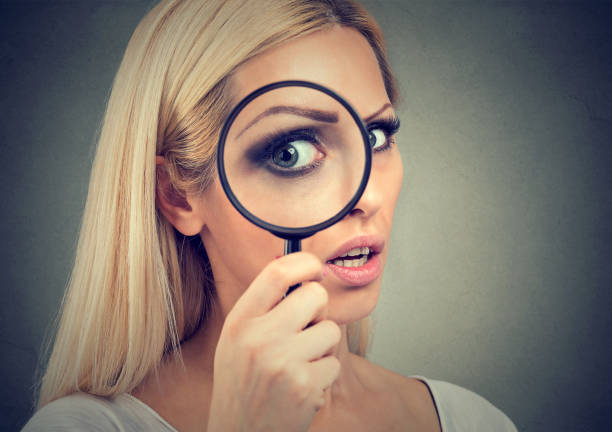 istock Curious woman looking through a magnifying glass 879950322