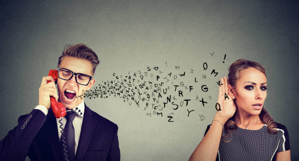 istock Angry man screaming over the phone while young woman eavesdropping on his conversation 879952480