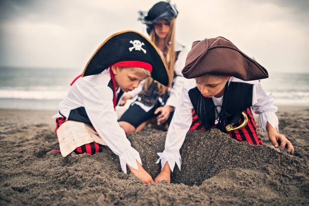 детские пираты читают карту сокровищ на пляже - lifestyles child beach digging стоковые фото и изображения