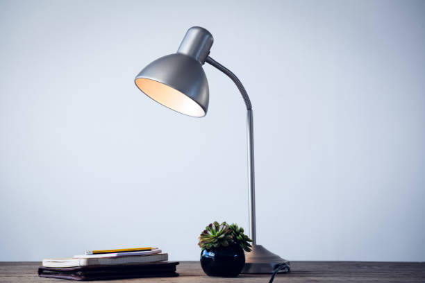 istock Illuminated desk lamp by books on table 879962086