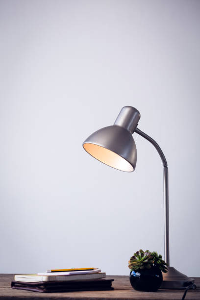 istock Illuminated electric lamp by books on table 879962092