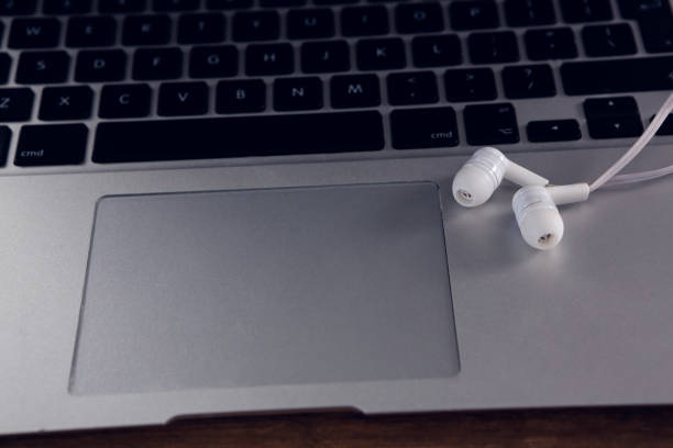 istock Earphones on laptop at wooden table 879969800