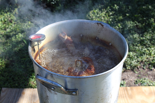 A turkey being deep fried in a cooking pot.