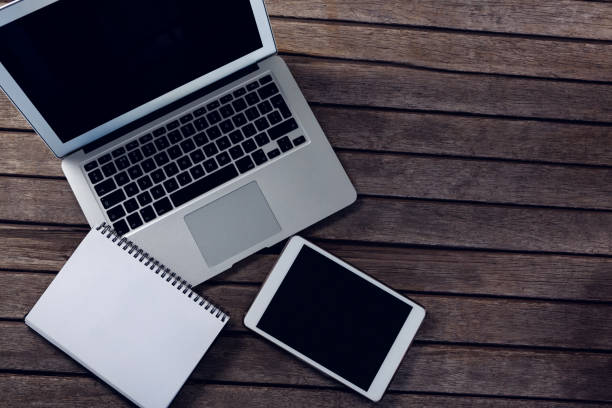 istock Laptop, digital tablet and diary on wooden table 879973366