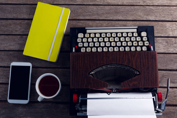 istock Vintage typewriter, diary, black coffee and smart phone on wooden table 879973442
