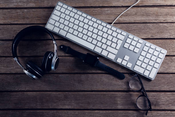 istock Headphones, spectacles, smartwatch and keyboard on wooden table 879977028
