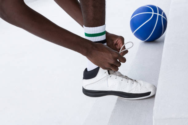 istock Basketball player tying shoelace on white background 879989586