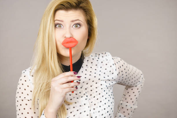 istock Happy woman holding fake lips on stick 879989706