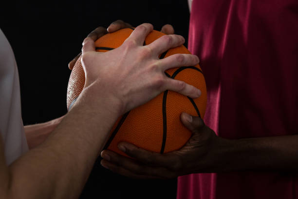 istock Competitors holding basketball against black background 879989718