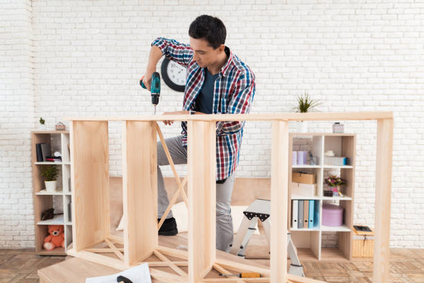 The young man tries himself to fold his bookcase.