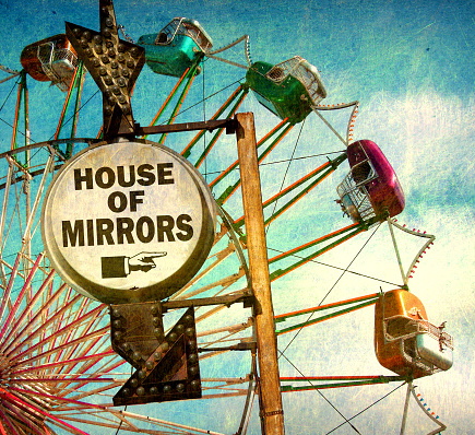 aged and worn house of mirrors sign with ferris wheel