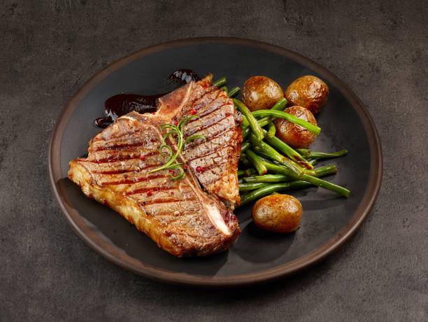 freshly grilled T bone steak freshly grilled T bone steak and vegetables on dark plate t bone steak stock pictures, royalty-free photos & images