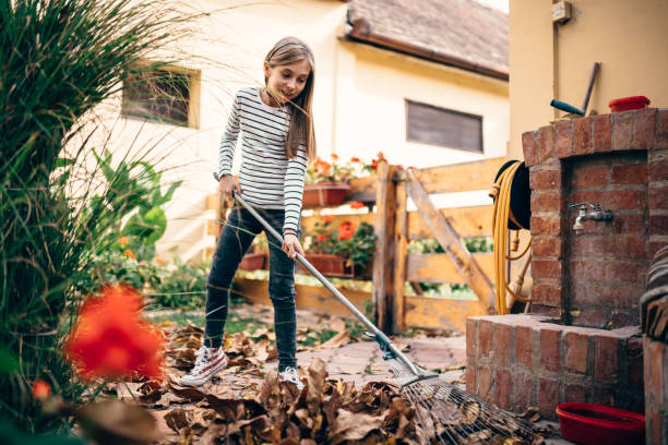 Girl raking up autumn leaves in garden