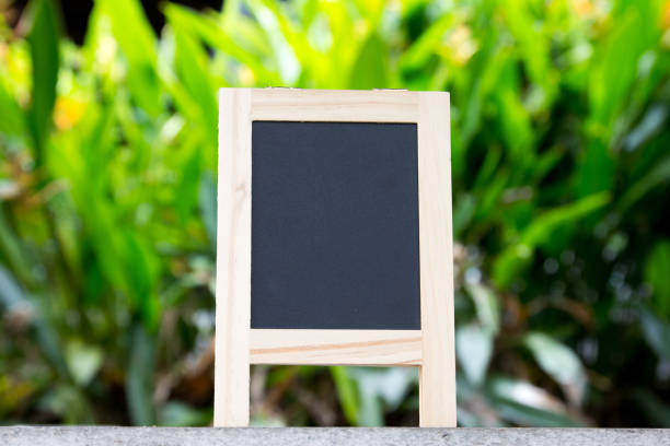 istock Black board with easel stand on green leaf background 880030872