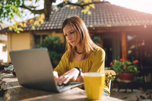 istock Women using laptop at backyard patio 880041400