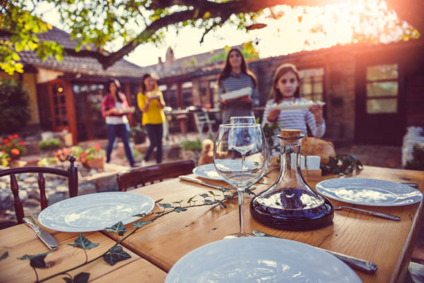 famiglia che prepara il tavolo da pranzo nel patio del cortile - thanksgiving table setting autumn foto e immagini stock