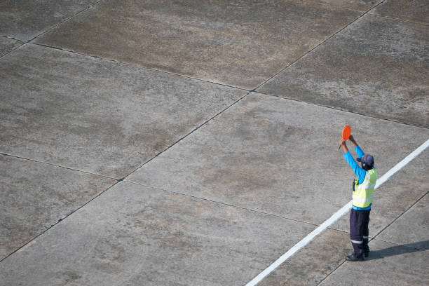 Marshaller signalling to stop the aircraft Marshaller signalling to stop the aircraft at the airport apron air traffic control operator stock pictures, royalty-free photos & images