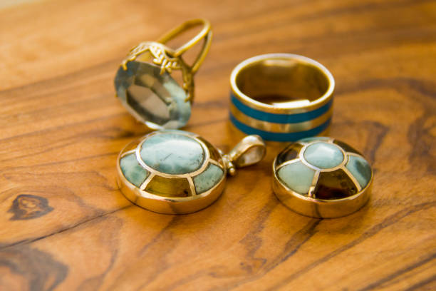 silver ornaments on the wooden floor, with stones and enamel azul; colgante; larimar; fondo; hermoso; naturaleza; piedra; grande; belleza; natural; objeto; colección; roca; superficie; plata; presente; áspero; planta ornamental; único; joyas; recuerdo; raro; que cura; piedras preciosas; gema; preciosos; mineral; dominicana; pectolita; soy