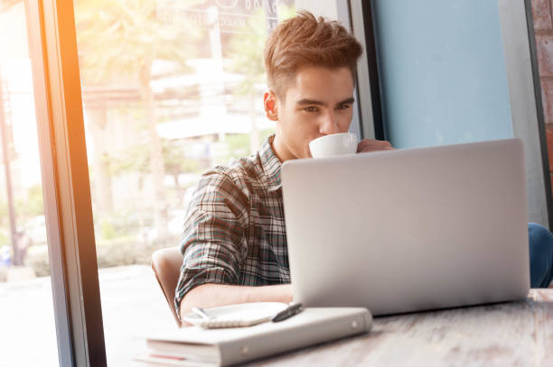 istock man drinking coffee with laptop on wooden table in coffee shop 880093224