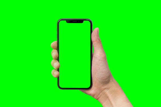istock Man's hand shows mobile smartphone with green screen in vertical position isolated on green background 880121622