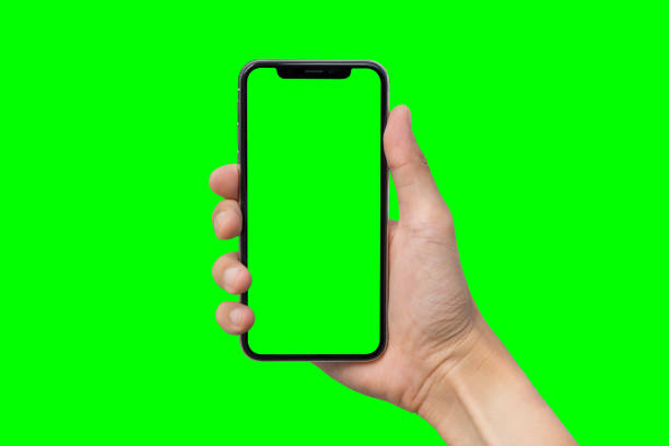 istock Man's hand shows mobile smartphone with green screen in vertical position isolated on green background 880121704