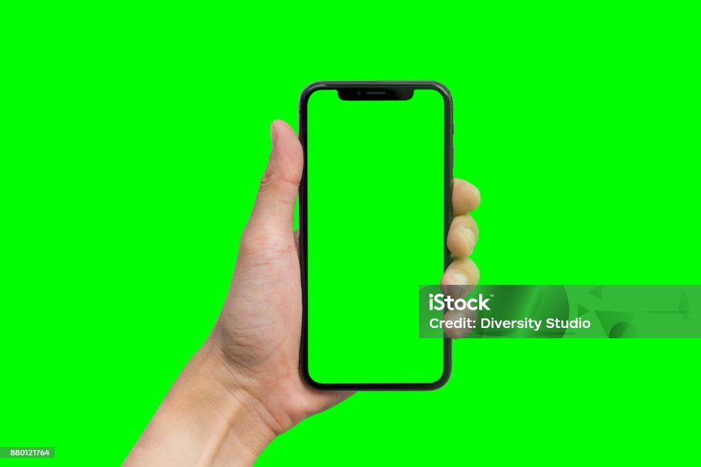 Hand des Mannes zeigt mobile Smartphone mit green Screen in vertikaler Position auf grünem Hintergrund isoliert - Lizenzfrei Farbstanze Stock-Foto