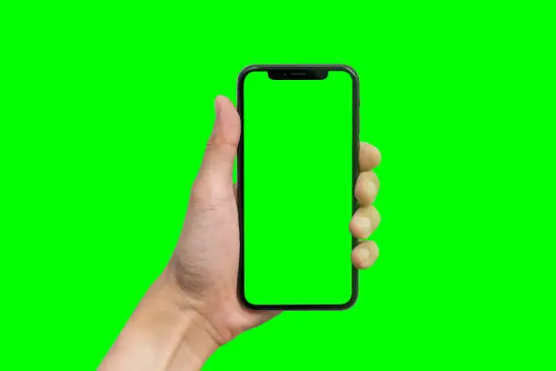 Man's hand shows mobile smartphone with green screen in vertical position isolated on green background