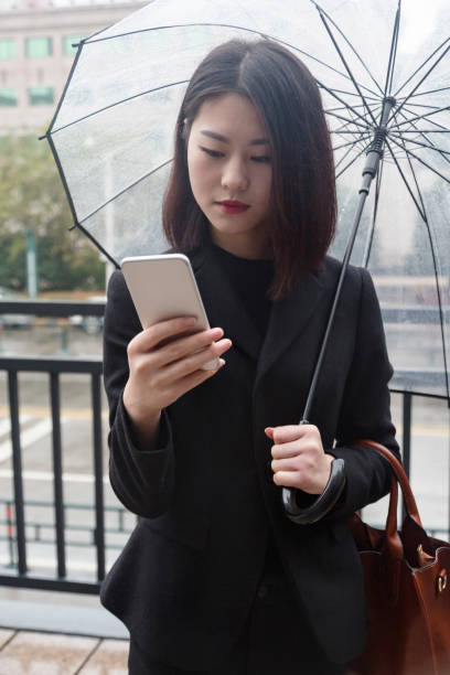 istock business woman using smartphone under umbrella 880123910