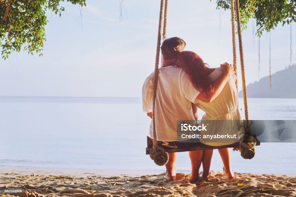 vacances romantiques, lune de miel, couple affectueux sur la plage sur la balançoire - Photo de Tous types de couple libre de droits