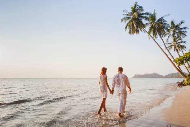 couple on the beach, romantic vacation, honeymoon romantic young couple walking together on beautiful exotic tropical beach at sunset honeymoon stock pictures, royalty-free photos & images