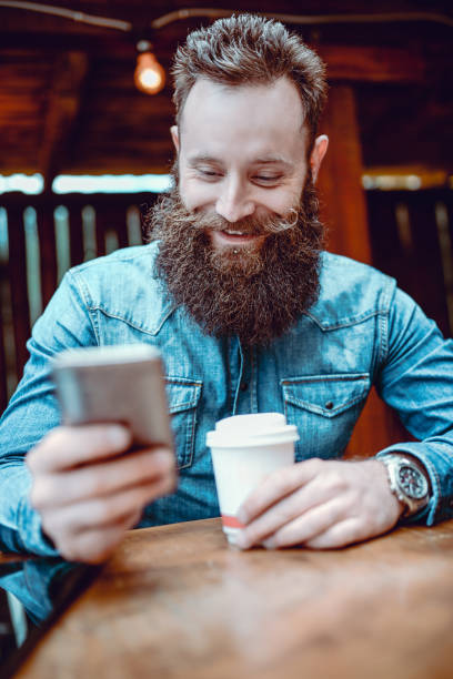 istock Handsome Smiling Hipster Person Texting and Drinking Coffee 880144042
