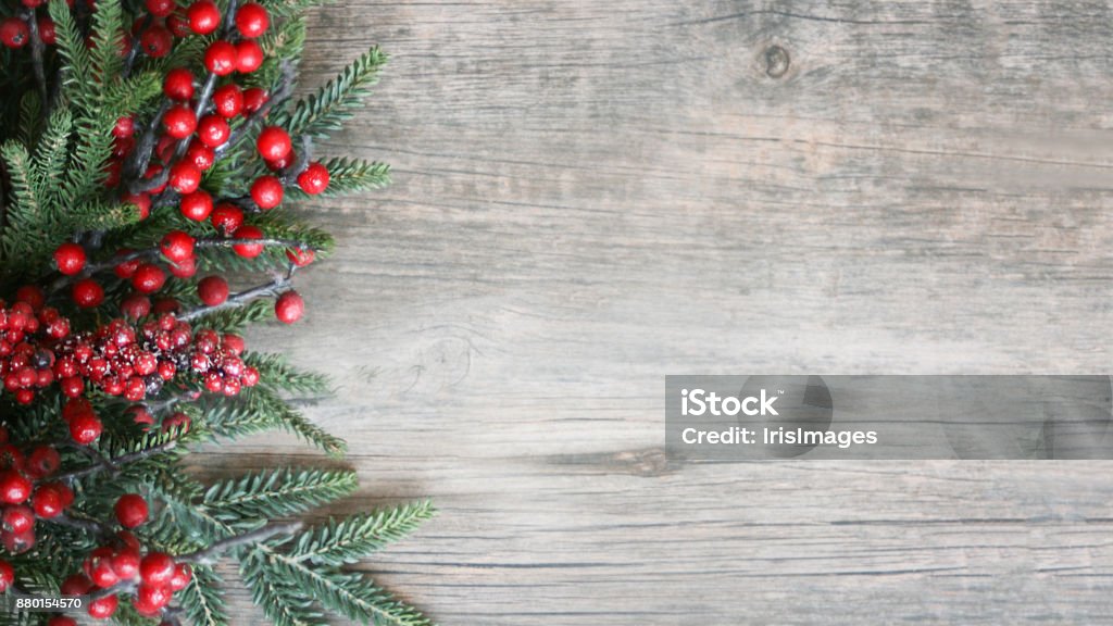 Holiday Evergreen Branches and Berries Over Wood Holiday Evergreen Branches and Berries Over Rustic Wood Background Christmas Stock Photo