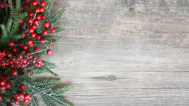 Holiday Evergreen Branches and Berries Over Rustic Wood Background
