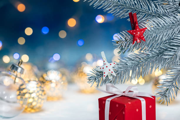 istock red gift box and silver christmas fir tree branch with decorations against blurred lights background 880172238