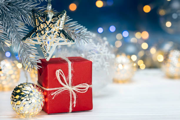 istock christmas tree decorations on fir tree branch and gift box against blurred lights background 880179780