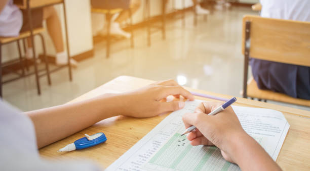 istock Uniform School Asian students taking exams writing answer optical form with pencil in high school classroom, view of having exams in class on seat rows, Education test and literacy concept. 880182808