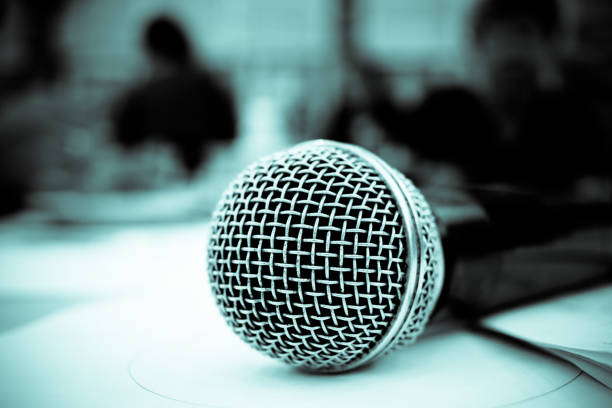 istock Microphone on abstract blurred of front podium and speech in seminar room or speaking conference hall light, Event meeting bokeh background, black and white tone 880185074