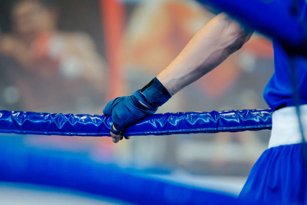 istock boxer man in corner boxing ring, hand with wraps on blue ropes 880185248