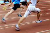 blurred motion group runners sprinters running on track stadium