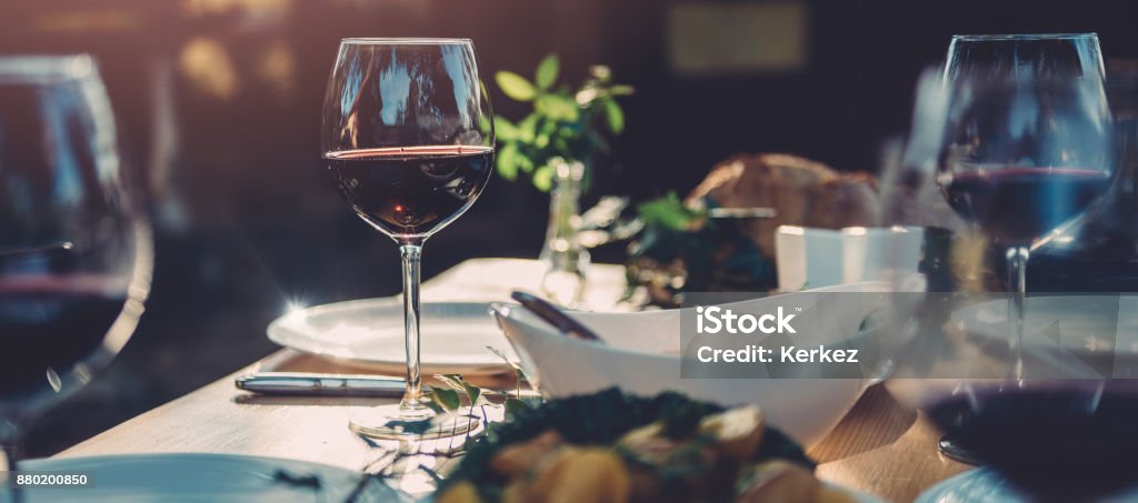 Glass of wine at dining table Glass of red wine at dining table in backyard patio Wine Stock Photo