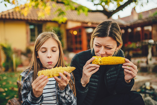 Portrait of two girls eating sweet corn outdoor
