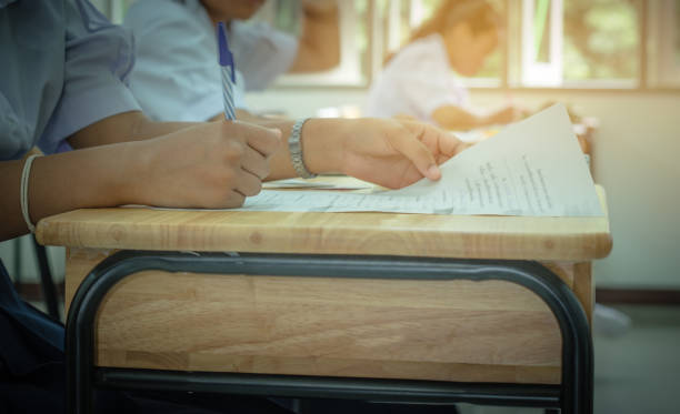 istock Asian School students in uniform taking examination and writing answer sheet in classroom, educational school, view of having exams in class on seat rows, Education system tests concept of Thailand 880205460