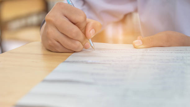 istock Students using pen writing information on white answer paper in high school, Asian exams room, Tests or examination is assessment intended to measure knowledge, skill, aptitude, Education Concept 880205470
