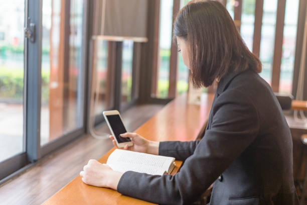 istock woman texting messages while reading a book in cafe 880214136