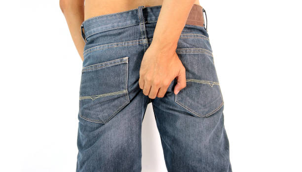 istock Young man with hand touching his bottom isolated on white background. 880220234