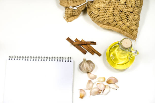 Notes to save the recipes on a white kitchen table. Seasonings, culinary ingredients - peppers, garlic and oil on the table. White background.
